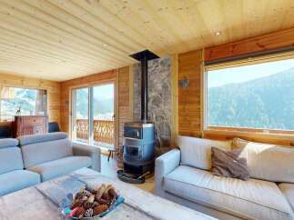 Experience breathtaking mountain views from this stunning living room, featuring a cozy wood-burning stove and ample natural light.