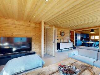 Experience rustic charm in this beautifully appointed log cabin living space, featuring a large flat-screen TV and comfortable seating.
