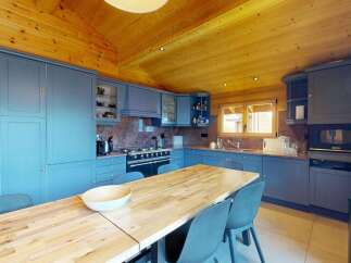 Experience rustic charm in this cozy kitchen featuring custom blue cabinetry and a warm, wood-paneled ceiling.
