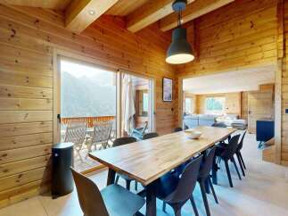 Experience luxurious mountain living in this stunning chalet, featuring a spacious dining area with a large wooden table perfect for gatherings.