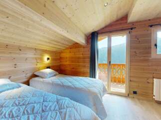 Experience cozy mountain living in this charming wooden bedroom featuring two comfortable twin beds, perfect for a restful night's sleep.