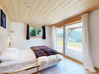 Experience breathtaking mountain views from this charming bedroom, featuring a cozy bed with plush bedding and a large sliding glass door that opens to a scenic vista.