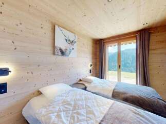 Experience serene mountain living in this charming alpine bedroom, featuring two cozy beds perfect for a restful night's sleep.