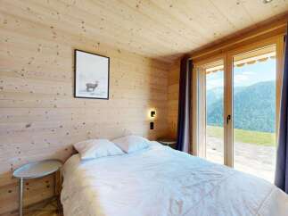 Experience breathtaking mountain views from this charming wooden cabin bedroom.