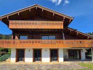 Experience alpine charm in this stunning wooden chalet, featuring intricate carved balconies on both levels.