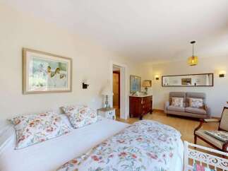 This charming bedroom offers a serene retreat with a comfortable bed adorned with floral linens and plush pillows.