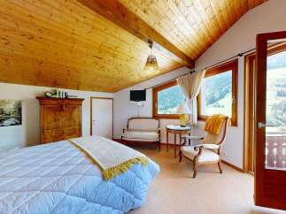 Experience breathtaking mountain views from this charming bedroom, featuring a cozy bed, elegant wooden furniture, and a private balcony.