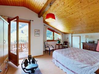Experience breathtaking mountain views from this charming bedroom, featuring a private balcony accessible through double doors.