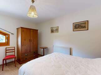 This charming bedroom features a large wooden wardrobe and a comfortable bed with a white duvet.