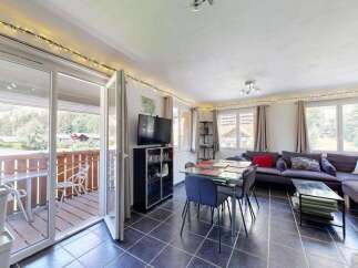 Enjoy mountain views from this charming living and dining area, featuring a spacious sectional sofa and a glass-top dining table perfect for family meals.