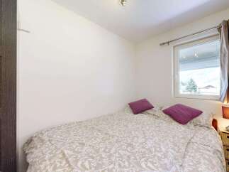 This cozy bedroom features a comfortable bed with a patterned duvet and two plush purple pillows.
