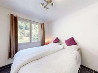 Experience comfort and style in this inviting bedroom, featuring a plush bed adorned with crisp white linens and accented by two vibrant purple throw pillows.