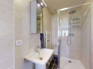 This modern bathroom features a sleek pedestal sink with a chrome faucet, complemented by a large mirror with integrated lighting.