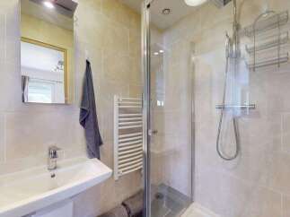 This modern bathroom features a sleek sink with a chrome faucet, complemented by a spacious glass-enclosed shower.