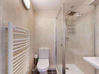 This modern bathroom features a sleek toilet and a spacious walk-in shower with a rainfall showerhead.