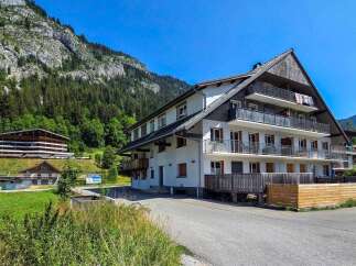 Discover this charming multi-story apartment building nestled in a serene mountain landscape.