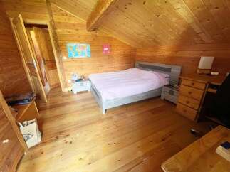 This charming wooden cabin bedroom features a comfortable bed with pink linens, complemented by a world map and a bunny decoration on the wall.