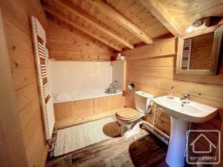 Experience rustic charm in this bathroom featuring a deep soaking tub, a modern pedestal sink, and a convenient toilet.
