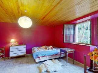 This charming bedroom features vibrant pink walls and a warm, wooden plank ceiling, creating a cozy and inviting atmosphere.