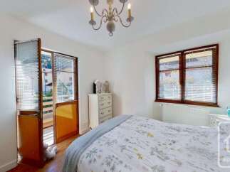 This charming bedroom features a comfortable bed with a floral duvet, complemented by a classic white dresser and a decorative chandelier.