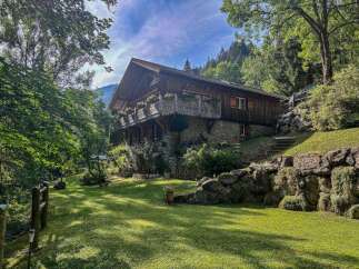 Nestled amidst lush greenery and a serene mountain backdrop, this charming wooden chalet offers a tranquil escape.