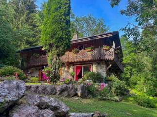 Nestled amidst lush greenery, this charming stone and wood chalet offers a serene mountain retreat.