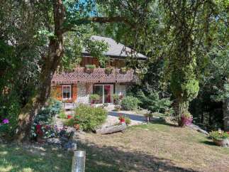 Nestled amidst lush greenery, this charming property boasts a picturesque facade with intricate wooden detailing and a welcoming stone exterior.