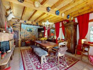 Experience rustic charm in this cozy dining area featuring a large wooden table, comfortable benches, and a traditional fireplace.