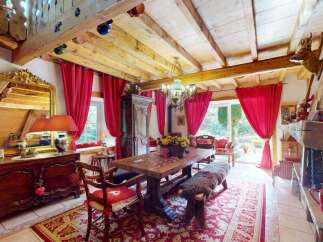 Experience rustic charm in this inviting dining room, featuring exposed wooden beams and vibrant red drapery.