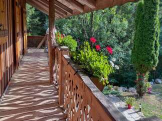 Experience the charm of this rustic wooden balcony, offering a serene escape amidst lush greenery.