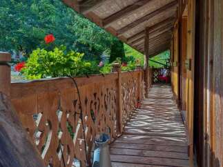 Experience rustic charm with this wooden balcony, featuring intricate carved railings and a sun-dappled wooden floor.