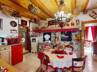 Experience rustic charm in this cozy kitchen and dining area, featuring exposed wooden beams and a stone fireplace.