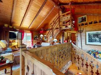 Experience rustic charm in this stunning wooden cabin, featuring a grand staircase and exposed beams that create a warm, inviting atmosphere.