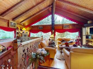 Experience rustic charm in this cozy wooden cabin living room, featuring plush leather sofas and a warm, inviting atmosphere.