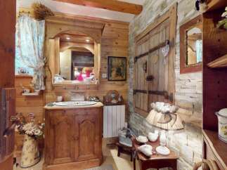 Step into a charming rustic bathroom featuring a wooden vanity with a porcelain sink, complemented by a large arched mirror.