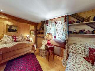 Experience rustic charm in this cozy bedroom featuring a wooden bed with floral bedding and a vibrant patterned rug.