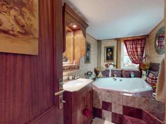 Experience rustic charm in this bathroom featuring a luxurious corner bathtub with elegant marble tiling.