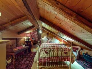 Discover this charming attic bedroom, featuring exposed wooden beams and a cozy, rustic ambiance.