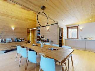 Experience modern alpine living in this stunning dining and kitchen area, featuring warm wood paneling and a sleek, contemporary design.