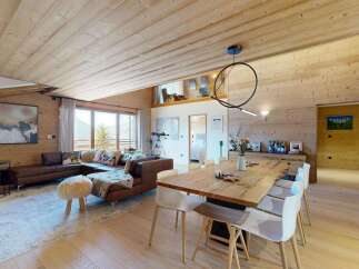 Experience luxury mountain living in this stunning chalet featuring a spacious open-plan living and dining area with a cozy sectional sofa and a large wooden dining table perfect for gatherings.