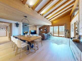 Experience luxury mountain living in this stunning chalet featuring a spacious open-plan living and dining area with a rustic wooden dining table and modern white chairs.