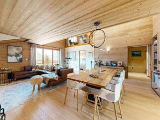 Experience luxurious mountain living in this stunning open-plan living and dining area, featuring a large sectional sofa, a rustic wooden dining table, and a modern chandelier.