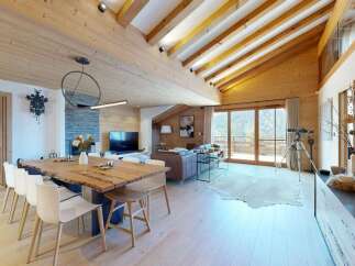 Experience luxury mountain living in this stunning chalet, featuring a grand wooden dining table perfect for gatherings and a cozy living area with a fireplace.