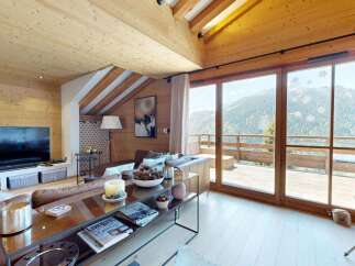 Experience luxurious mountain living in this stunning chalet featuring a spacious living area with a large television and comfortable seating.