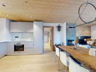Experience modern alpine living in this stunning open-plan space, featuring a sleek, integrated kitchen with ample counter space and a built-in oven.