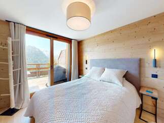 Experience mountain living in this charming bedroom featuring a cozy bed and a stunning view from the private balcony.