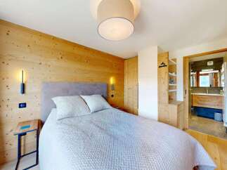 Experience cozy mountain living in this charming bedroom featuring warm wood-paneled walls and a comfortable bed.