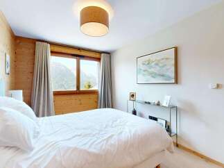 Experience serene mountain living in this charming bedroom, featuring a cozy bed dressed in crisp white linens and a stunning landscape painting above a sleek console table.