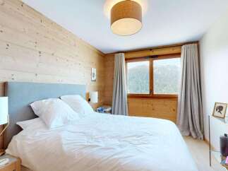 Experience cozy mountain living in this charming bedroom featuring natural wood paneling and a plush bed.