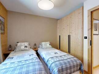 This charming bedroom features two twin beds with cozy, patterned bedding and adorable elephant motifs on the pillows.